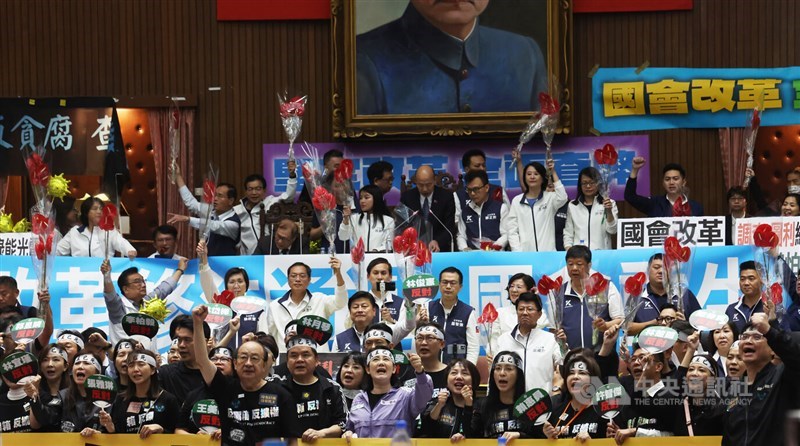 KMT lawmakers in the back hold flowers to celebrate the passing of an amendment to the Criminal Code, which added "contempt of Legislature" as a legally punishable offense, while DPP lawmakers in the front chant slogans in protest, in the Legislative Yuan when the reform bills cleared the legislative floor on May 28, 2024. Photo: CNA